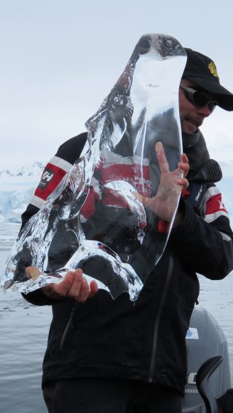 An Antarctica guide holding a huge chunk of ice